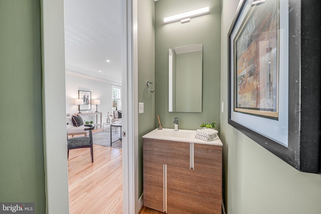 bathroom with vanity, wood finished floors, and crown molding