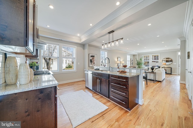 kitchen with light wood-type flooring, a sink, dark brown cabinets, stainless steel dishwasher, and open floor plan