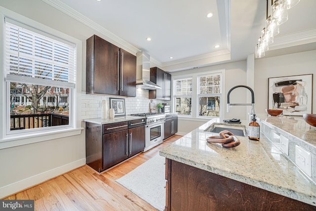 kitchen with high end stainless steel range, ornamental molding, a sink, dark brown cabinetry, and wall chimney exhaust hood