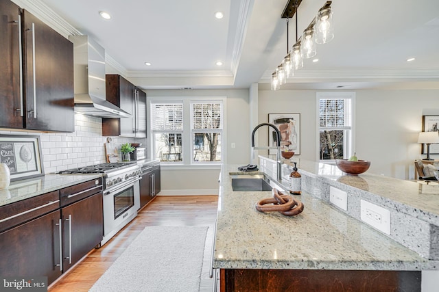 kitchen featuring a sink, wall chimney exhaust hood, high end range, and ornamental molding