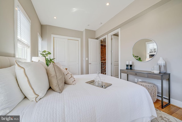 bedroom featuring a closet, recessed lighting, multiple windows, and wood finished floors