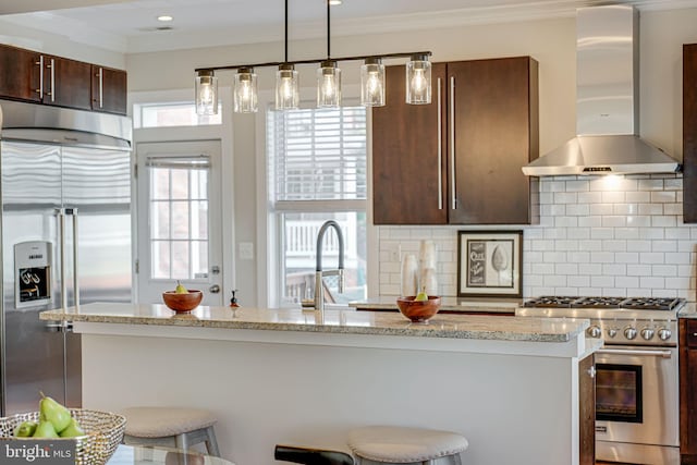 kitchen featuring a breakfast bar, ornamental molding, exhaust hood, high quality appliances, and tasteful backsplash