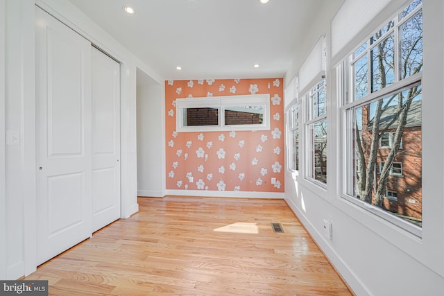 unfurnished room with visible vents, light wood-style flooring, recessed lighting, wallpapered walls, and baseboards