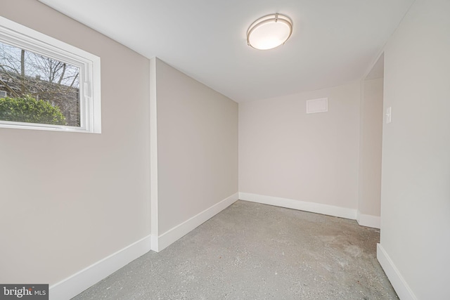 empty room with baseboards and concrete flooring