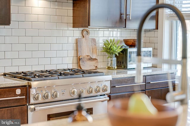 interior details featuring light stone counters, decorative backsplash, dark brown cabinets, and stainless steel range