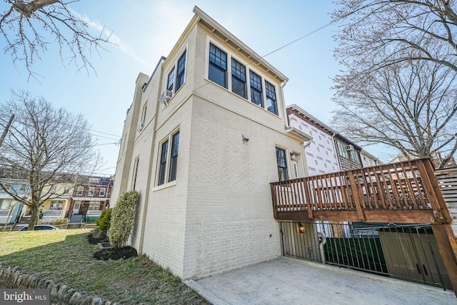 view of home's exterior featuring a wooden deck, brick siding, and a lawn