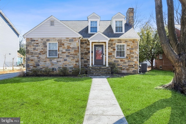 new england style home with roof with shingles, a front lawn, a chimney, and central air condition unit