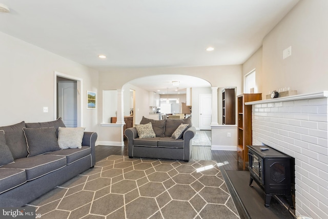 living area featuring dark wood-style floors, arched walkways, recessed lighting, ornate columns, and baseboards