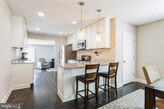 kitchen featuring stainless steel appliances, white cabinetry, light stone counters, and dark wood-style floors