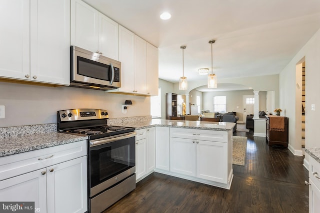 kitchen featuring arched walkways, white cabinets, appliances with stainless steel finishes, a peninsula, and ornate columns