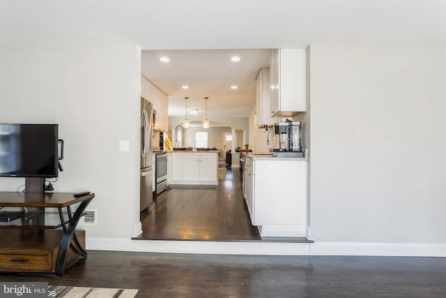 kitchen featuring arched walkways, dark wood-style flooring, stainless steel appliances, white cabinets, and baseboards