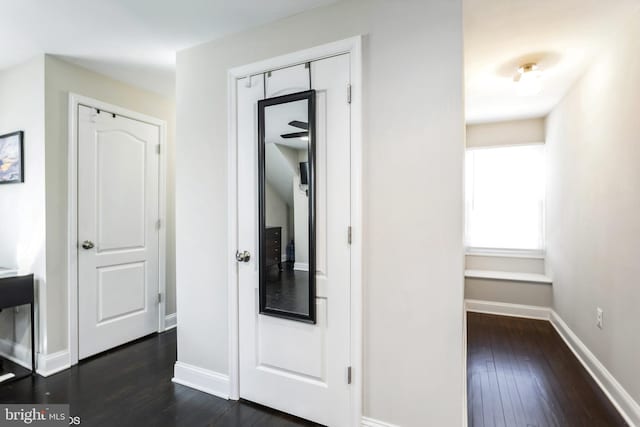 hallway featuring dark wood-style floors and baseboards