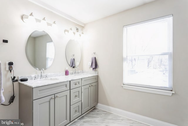 bathroom with double vanity, marble finish floor, baseboards, and a sink