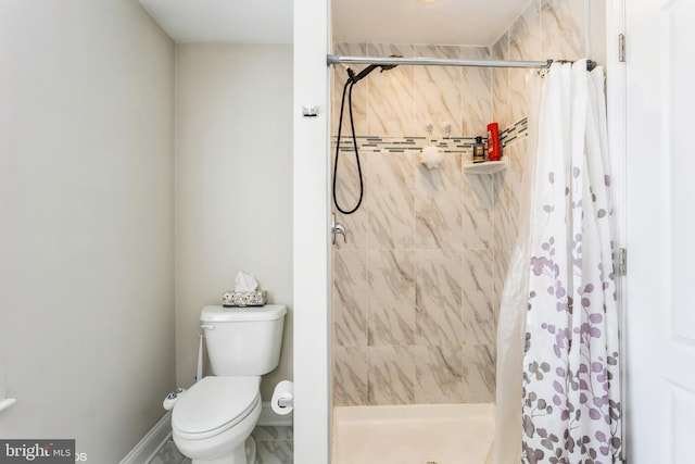 bathroom featuring a shower stall, toilet, and baseboards