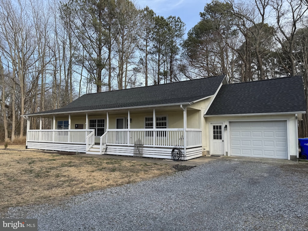 view of front of house with covered porch, driveway, roof with shingles, and a garage