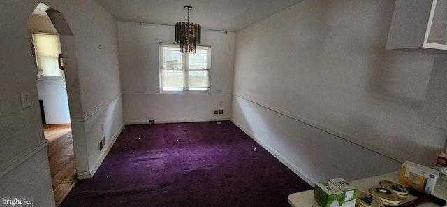 unfurnished dining area featuring a chandelier, arched walkways, visible vents, and baseboards