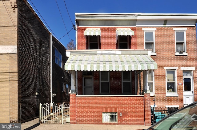 view of front of property with a gate and brick siding