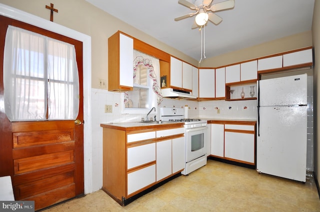 kitchen featuring white appliances, a sink, exhaust hood, white cabinets, and light countertops