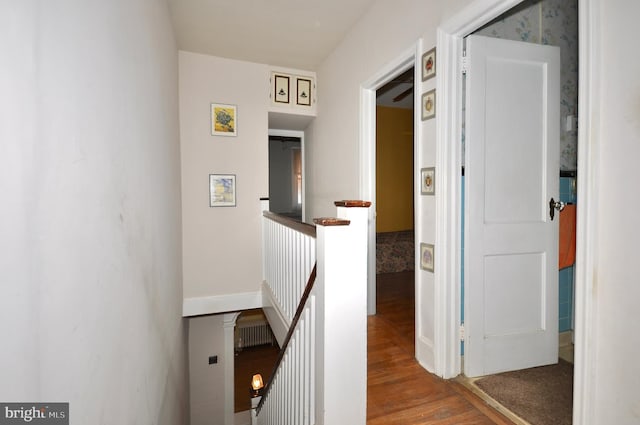 hall featuring baseboards, wood finished floors, and an upstairs landing