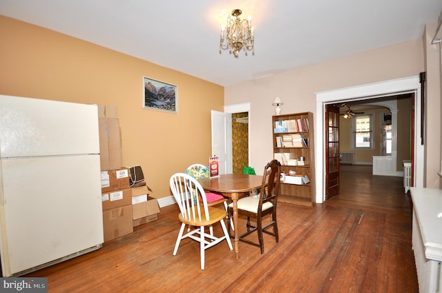 dining space with a chandelier, radiator heating unit, hardwood / wood-style flooring, and baseboards