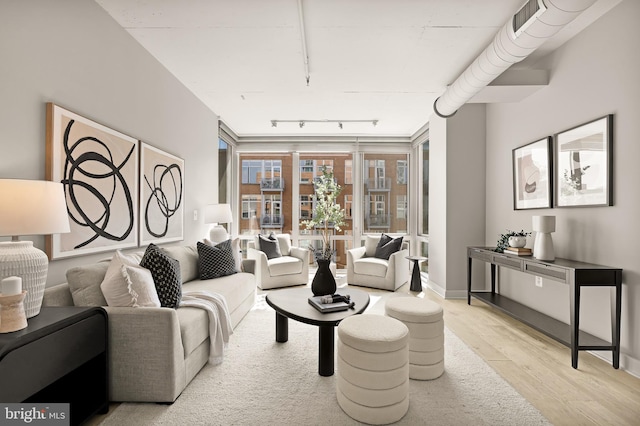 living area with visible vents, light wood-style floors, and rail lighting