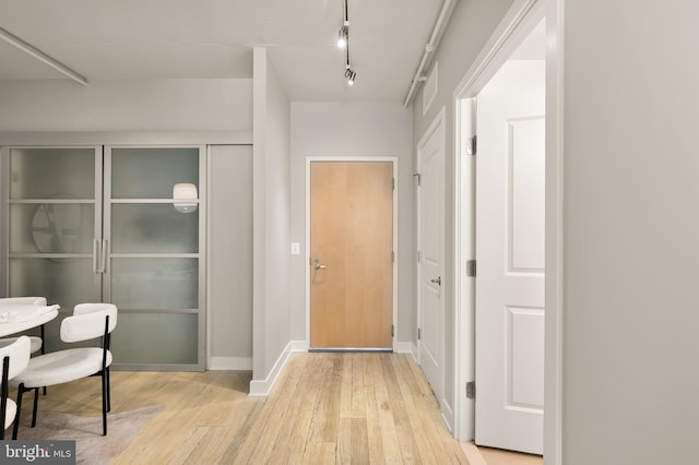 foyer entrance with baseboards, light wood-style floors, and track lighting