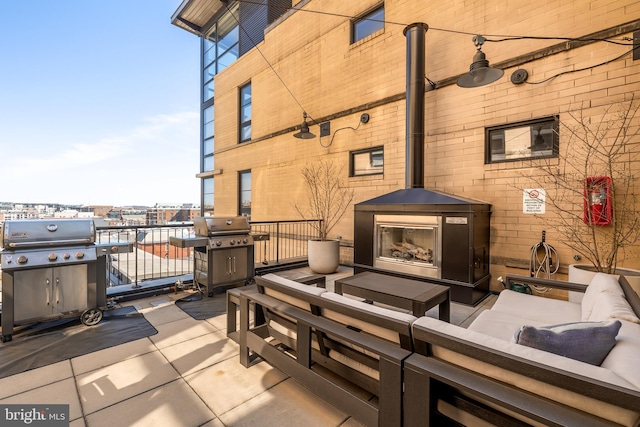 view of patio with an outdoor living space with a fireplace and a grill