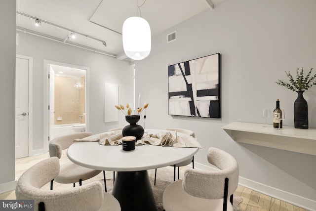 dining area with track lighting, baseboards, visible vents, and light wood finished floors