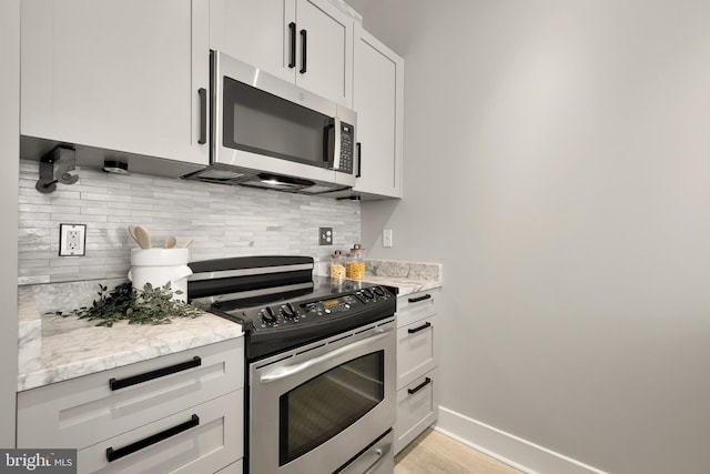 kitchen featuring light stone counters, baseboards, backsplash, and appliances with stainless steel finishes