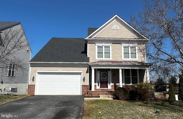 traditional-style house featuring brick siding, an attached garage, central air condition unit, driveway, and a standing seam roof