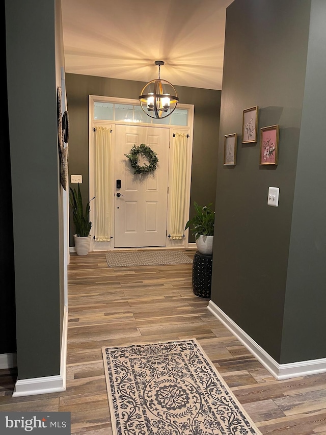 foyer featuring a notable chandelier, baseboards, and wood finished floors