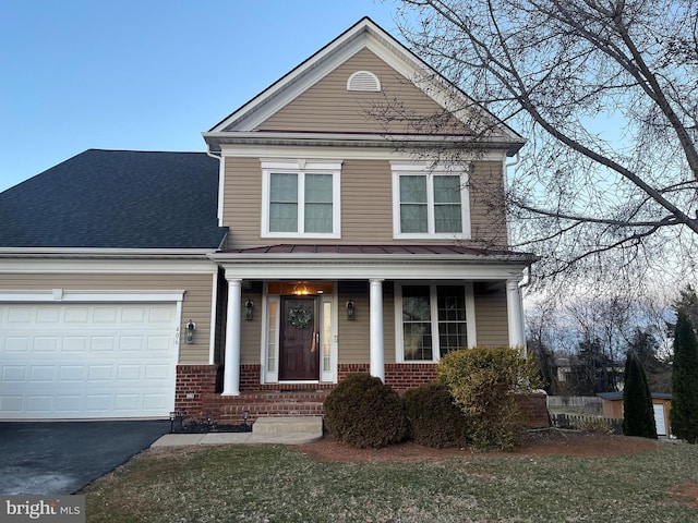 traditional-style home featuring driveway, covered porch, an attached garage, and brick siding