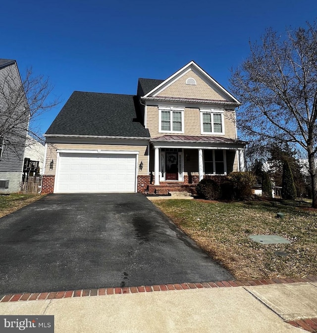 traditional home with covered porch, brick siding, an attached garage, and aphalt driveway