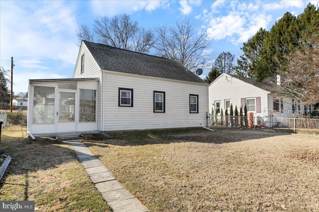 back of property with a shingled roof, a lawn, a sunroom, and fence private yard