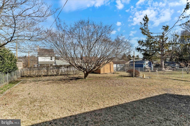 view of yard with a fenced backyard, an outbuilding, and a storage shed