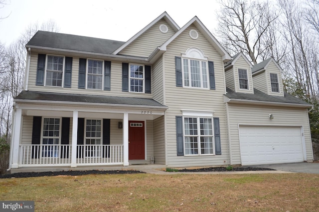 view of front of house with a garage, a front yard, a porch, and driveway