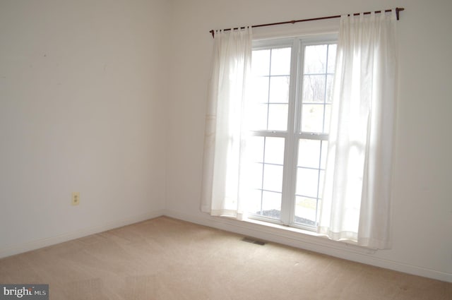 unfurnished room with a wealth of natural light, visible vents, baseboards, and carpet