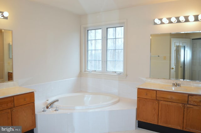 full bath with plenty of natural light, a garden tub, and vanity