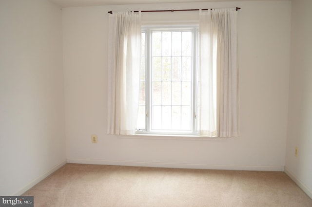 empty room featuring light carpet, a healthy amount of sunlight, and baseboards