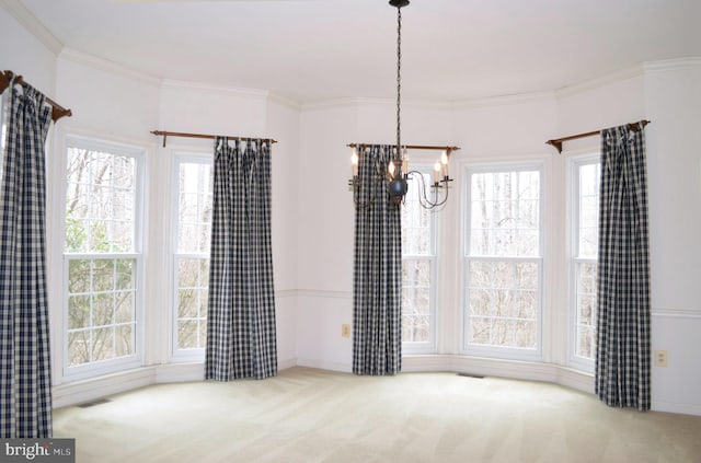 unfurnished dining area with crown molding, carpet flooring, and a chandelier