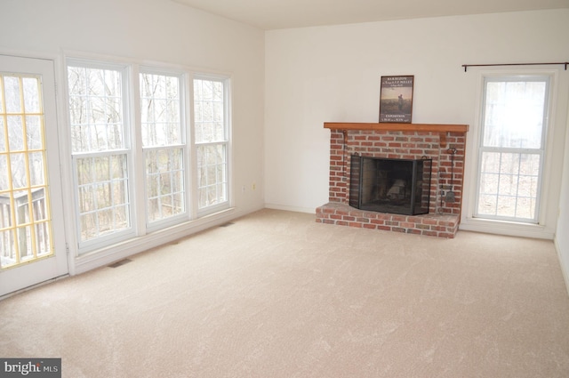 unfurnished living room featuring a wealth of natural light, visible vents, carpet floors, and a fireplace