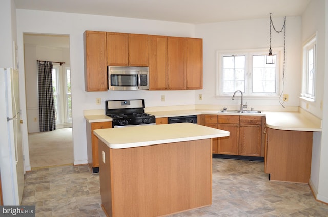 kitchen with light countertops, a center island, appliances with stainless steel finishes, and a sink