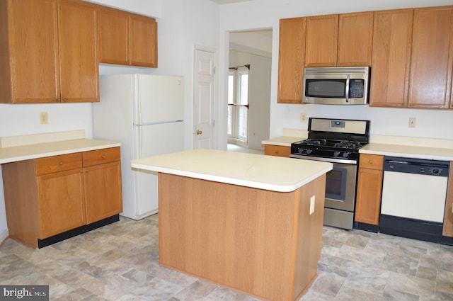 kitchen with a kitchen island, stone finish flooring, light countertops, brown cabinets, and appliances with stainless steel finishes