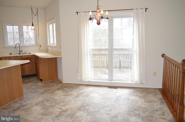 kitchen with a sink, a notable chandelier, light countertops, and hanging light fixtures