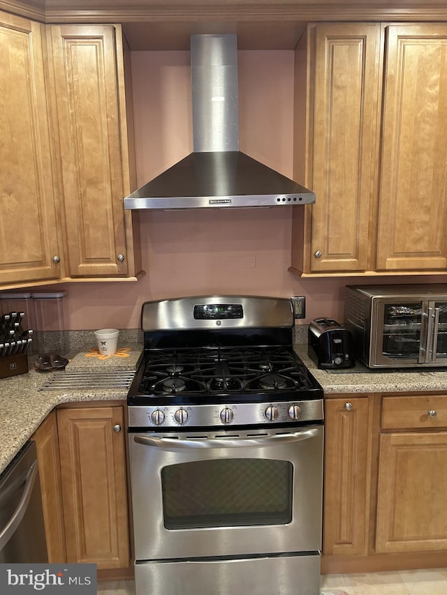 kitchen with light stone countertops, wall chimney exhaust hood, a toaster, and stainless steel appliances