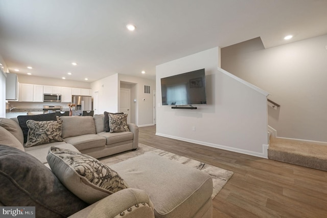 living room featuring stairs, baseboards, light wood-style flooring, and recessed lighting