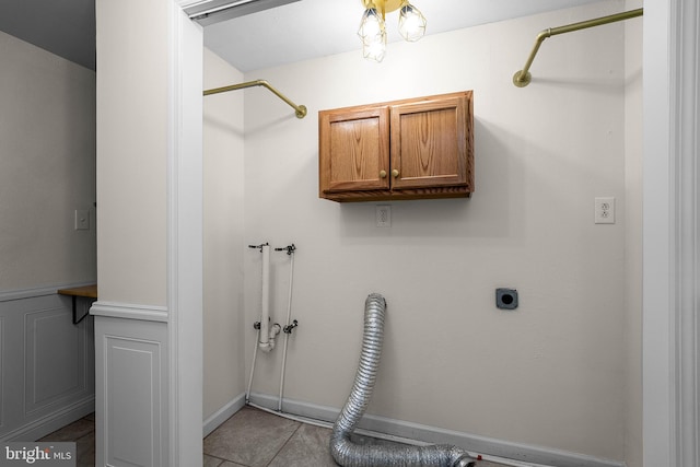 washroom featuring cabinet space, hookup for an electric dryer, and light tile patterned floors