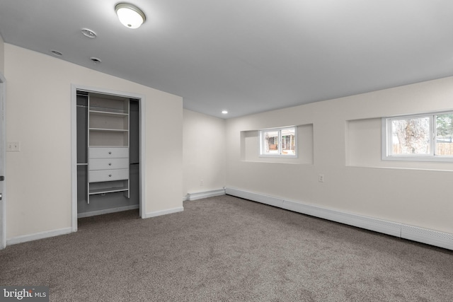 unfurnished bedroom featuring carpet floors, a baseboard radiator, multiple windows, and baseboards