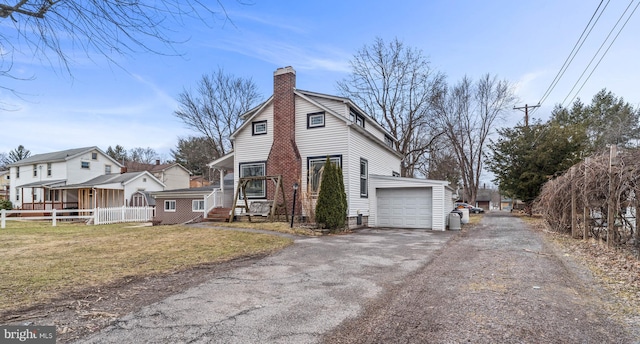 view of home's exterior featuring driveway, a chimney, fence, and a yard