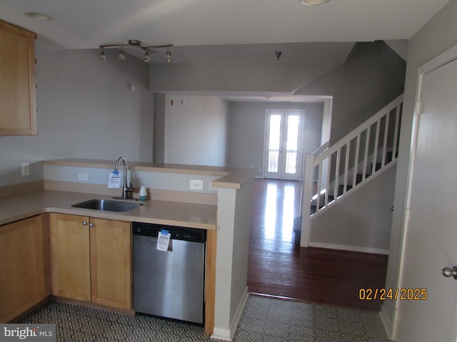 kitchen with a peninsula, a sink, light countertops, stainless steel dishwasher, and light brown cabinetry